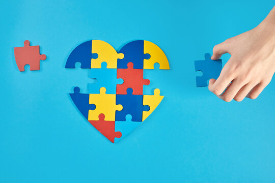 Autistic boy hands holding jigsaw puzzle heart shape. World Autism Awareness Day