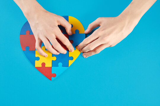 Autistic boy hands holding jigsaw puzzle heart shape. World Autism Awareness Day