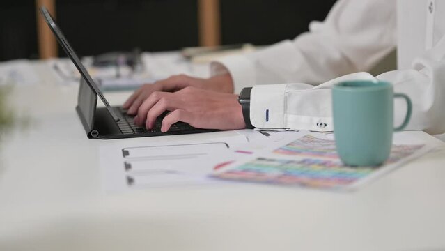 Shot of man website developer typing on keyboard of digital tablet, working design project at modern office