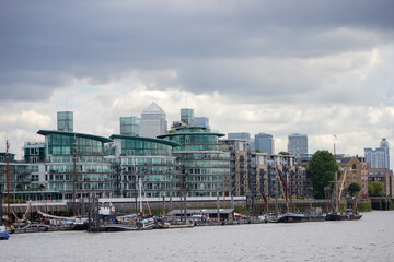 Barges moored on the River Thames in front of apartment buildings, Wapping, London, UK.