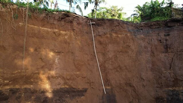 Edge of collapsed road due to landslide, unusual perspective: low angle panning shot. Dangerous calamity, ground fall down and house compound now in great risk