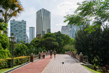 Kuala Lumpur, Malaysia: People on the Jogging Track crossing the footbridge in KLCC Park surrounded...