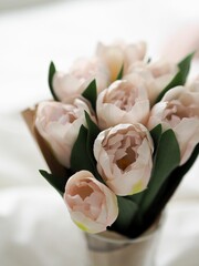 Vertical closeup of a small pretty bouquet of white tulips in a vase in the bedroom