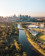 Drone vertical shot of the Melbourne cityscape with a river and green trees on a sunny day