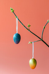 Fresh flowering branches decorated with colorful Easter eggs on a pink background. Holiday concept, home decoration, happy childhood and family traditions.