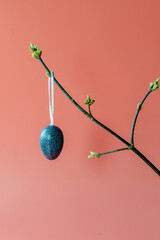 Fresh flowering branches decorated with colorful Easter eggs on a pink background. Holiday concept, home decoration, happy childhood and family traditions.