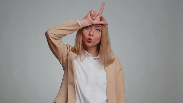 Business woman showing loser gesture and pointing on you, blaming accusing for unsuccess, expressing disrespect, mocking your failure, bullying abuse. Female girl in suit. Woman on gray background