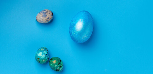 Easter background with blue Easter eggs and spring flowers on a blue background. Top view, space for text, banner