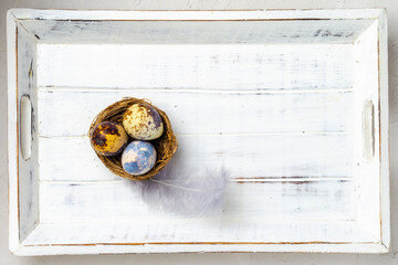 Easter small multi-colored eggs on a white wooden background. Minimal concept. View from above. Card with copy space for text