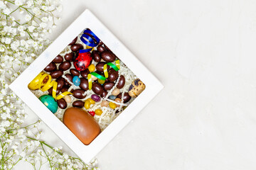 Festive Easter background. Easter colorful eggs with flowers on a white table. Flat styling