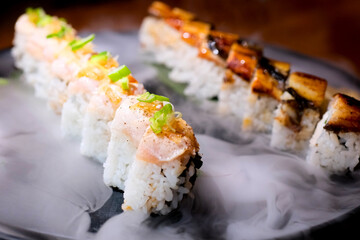 chic serving of sushi with tuna and eel on stone plate with dry ice delicious appetizing unusually ad of sushi bar of California sushi set restaurant on palm leaves sticks serving incredibly desirable