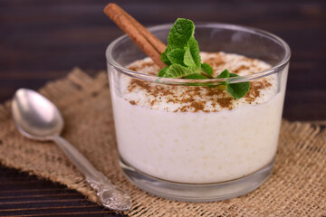 Rice pudding with cinnamon in a glass on a dark wooden background.Close-up.	