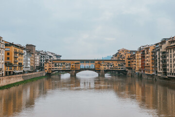 Fototapeta na wymiar Colorful symmetrical old famous bridge by the river in italian town