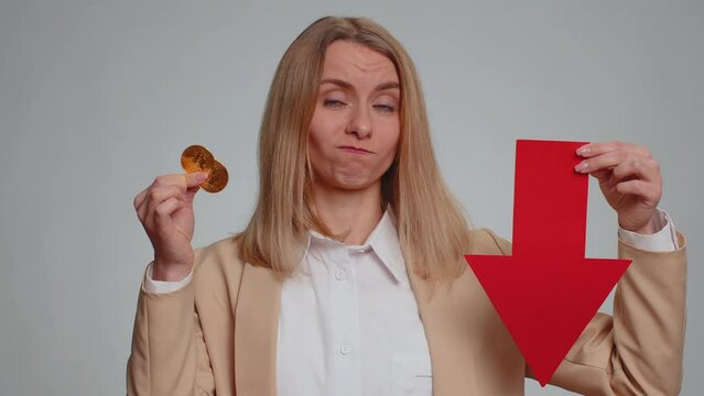 Business woman showing golden bitcoins indicating red arrow banner down sign decrease of exchange rate. Unsuccessful bankruptcy fall of stock cryptocurrency market investment mining BTC technology
