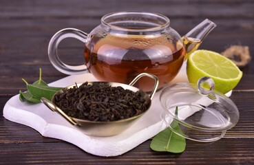 Tea in a transparent teapot on a white wooden board.
