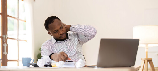 Young african man working at the office using computer laptop suffering pain on hands and fingers, arthritis inflammation