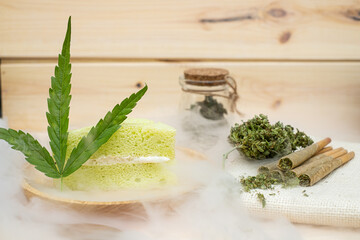 Pre-Roll cannabis joints and cake with cannabis buds in a clear glass jar laying on the sackcloth