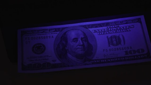 verification of counterfeit money in ultraviolet. UV check of USD banknotes. Money falsification concept background. In-depth inspection equipment. Equipment for in-depth inspection of money