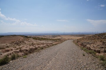 Fototapeta na wymiar Road in a deserted area landscape with bare hills