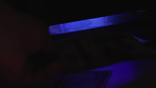 verification of counterfeit money in ultraviolet. UV check of USD banknotes. Money falsification concept background. In-depth inspection equipment. Equipment for in-depth inspection of money