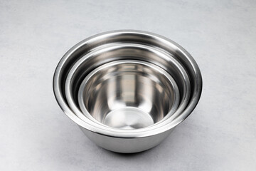 Set of 3 stainless steel bowls. Each bowl at different size. Kitchen accessories on a bright table.