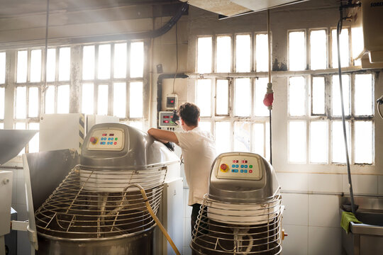 Worker with his back turned with machines in his kitchen and a nice light.