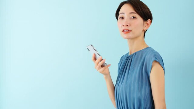 スマートフォンを使うワンピースを着た若い女性