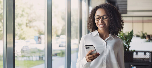 Business woman using smartphone in modern office, banner. Student girl texting on mobile phone indoors. Communication, connection, mobile apps, technology, business lifestyle concept - Powered by Adobe