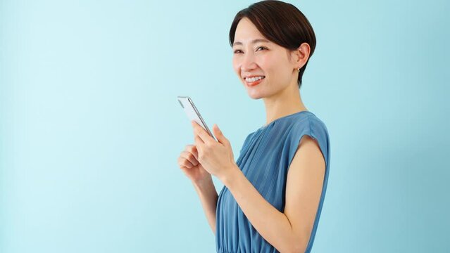 スマートフォンを使うワンピースを着た若い女性