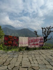 Vertical shot of prayer rugs hung to dry high up in the mountains under cloudy sky.