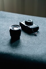 Vertical shot of a black photo camera and lens on a gray surface on an isolated background