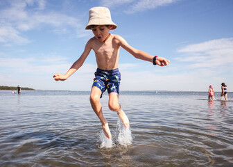 Young boy jumping in the water at the beach