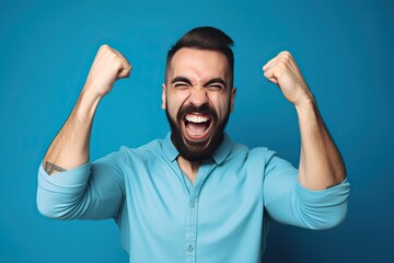 Fototapeta premium Portrait of a Man with Fists in the Air Celebrating Success,/Win on a Blue Background (Generative Ai)