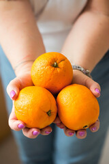Woman holding three oranges in hands - 582515856