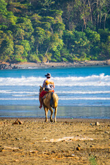 Costa Rican cowboy riding his horse on the beach in Jaco, Costa Rica
