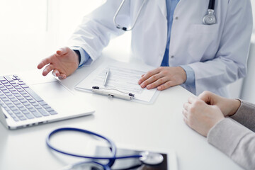 Doctor and patient discussing current health questions while sitting at the table in clinic office, only hands closeup. Medicine concept