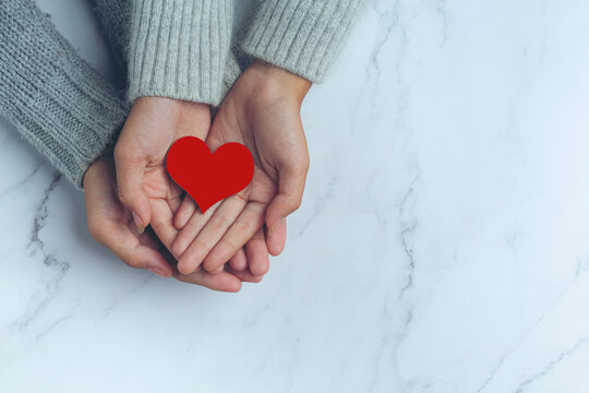 paper heart put in couple's hands on marble table