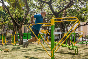 Mature man workout exercises in outdoor fitness park