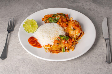 Delicious Brazilian fish moqueca with tomato, onion, olive oil, coriander and orocum seed. Served on a white porcelain plate with rice