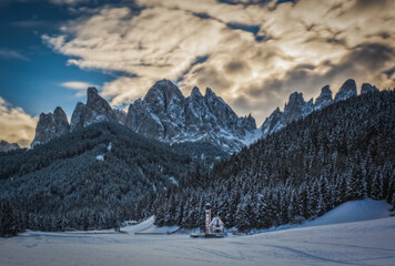 St. Magdalena or Santa Maddalena with its characteristic church in front of the Geisler or Odle dolomites mountain peaks in the Val di Funes Villnosstal in Italy in winter. January 2023. Long exposure