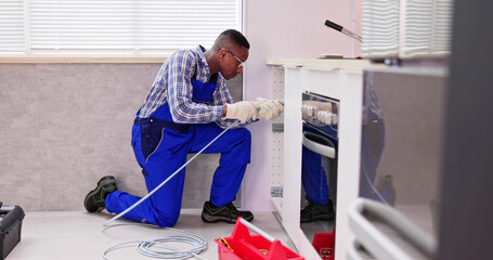 Young Male Plumber Cleaning Clogged Sink Pipe