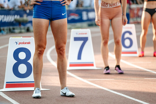 legs group female athletes start running middle distance race at stadium, spikes shoes for running Nike, polanik lane markers