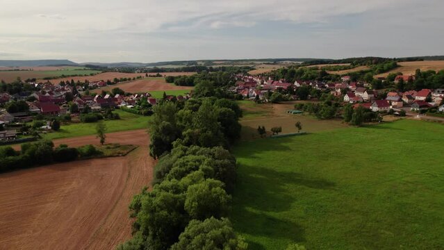 Aer ial view of a German village surrounded by meadows, farmland and forest in Germany.