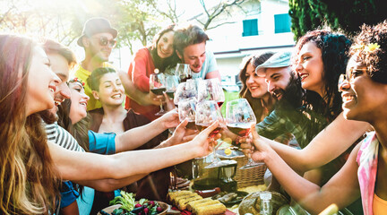 People group toasting red wine having fun outdoor cheering at bbq picnic - Young friend enjoying summer together at garden party out side - Friendship life concept with focus on glasses - Vivid filter