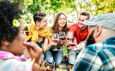 Young friends having fun out side toasting wine at picnic party - Happy people eating and drinking in farm house winery at afternoon - Food and beverage life style concept on warm vivid filter