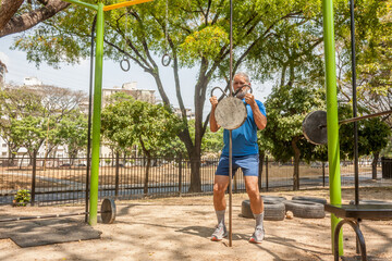 Mature man workout exercises in outdoor fitness park