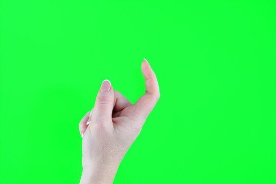 beckon with a finger female index finger crooked reckoning come over here isolated on green background. High quality photo