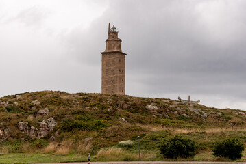 Fototapeta na wymiar The Torre de Hercules, an ancient Roman lighthouse and a symbol of La Coruña, Galicia, Spain, stands tall against the blue sky, offering a glimpse into the region's rich history and culture