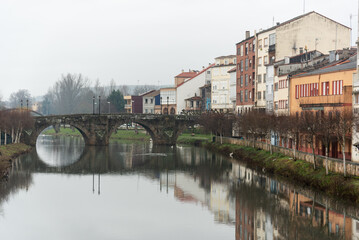 Fototapeta na wymiar In Orense, Spain, a picturesque bridge spans a calm river surrounded by trees