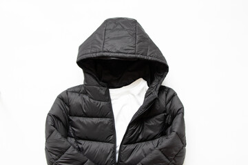 Black puffy winter jacket lies on a white background, fashionable winter clothes